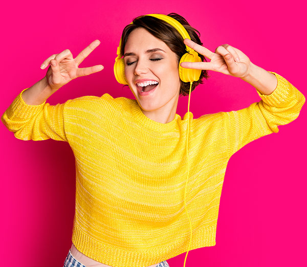 Frau hört Musik auf Kopfhörern und tanzt dabei